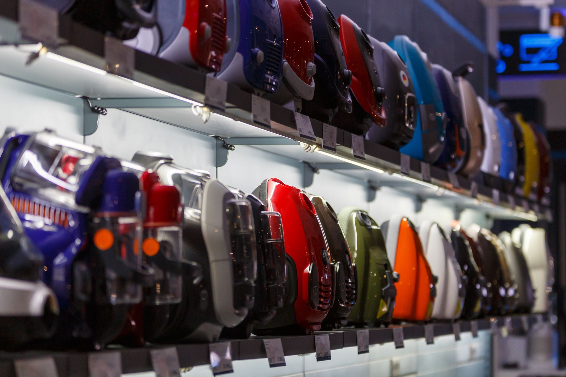 row of domestic vacuum cleaners on shelf of household appliances store